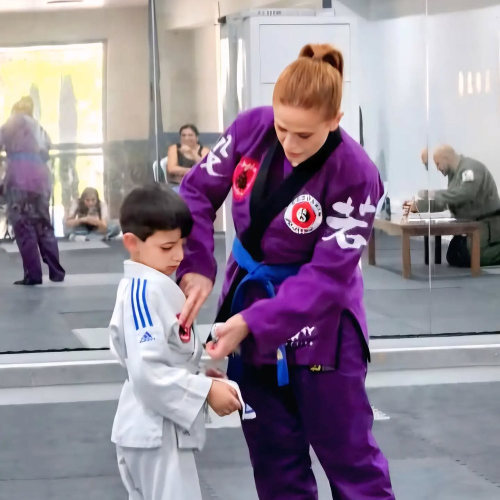 An instructor adjusting a young student's gi during class